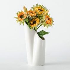 a white vase filled with yellow and orange flowers