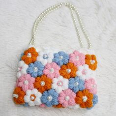 a handbag with flowers and pearls on it sitting on a white furnishing