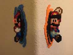 two pieces of art made out of legos are hanging on the wall next to each other