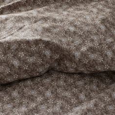 a bed covered in a brown and white flowered comforter next to a pillow