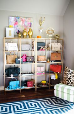 a living room filled with lots of purses and handbags on shelving units