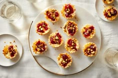 small desserts are arranged on white plates with silverware and wine glasses in the background