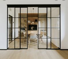 an open glass door leading to a dining room with wooden floors and white walls in the background