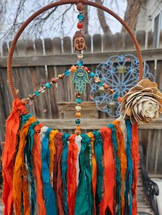 an orange and blue dream catcher hanging from a wooden hoop with beads, feathers and a flower