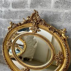 an ornate gold framed mirror against a brick wall