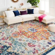 a living room with white couches, colorful rug and large mirror on the wall