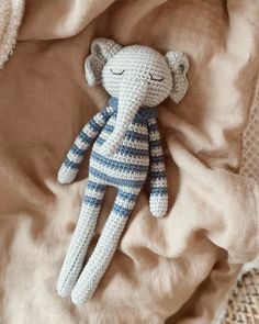 a crocheted stuffed animal laying on top of a bed next to a blanket