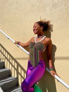 a woman in purple and green is posing on the stairs