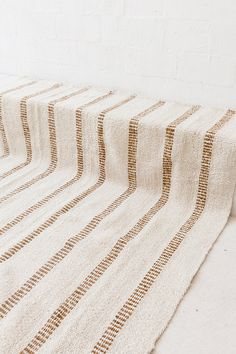 a white and brown striped rug sitting on top of a floor next to a wall