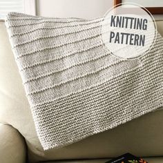 a knitted blanket sitting on top of a couch next to a book