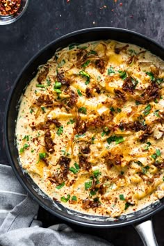 a skillet filled with food on top of a black counter next to other dishes