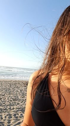 a woman standing on top of a beach next to the ocean