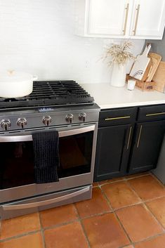 a stove top oven sitting inside of a kitchen next to black cabinets and counter tops