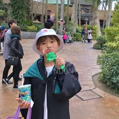 a young boy in a hat and coat eating something