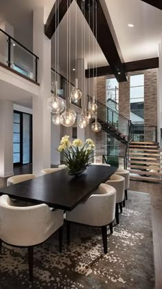 a dining room table with white chairs and chandelier hanging from it's ceiling