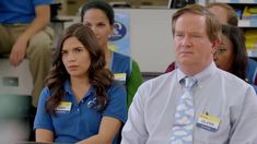 a group of people sitting next to each other in front of a man wearing a blue shirt and tie