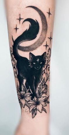 a black cat sitting on top of a flower next to a moon and star tattoo