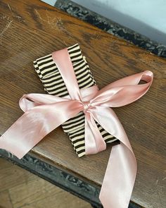 two napkins tied together with pink ribbon on top of a wooden table next to a wall