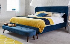 a bedroom with a blue bed and yellow blanket on the headboard, white walls and carpet