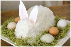 a cake with white frosting and bunny ears in the center, surrounded by eggs