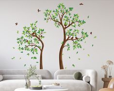 a living room with two trees painted on the wall and one tree has green leaves