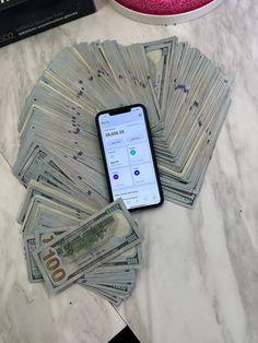 a cell phone sitting on top of a pile of money next to a bowl of cash