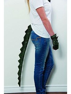 a woman standing in front of a white wall with a green dragon on it's back