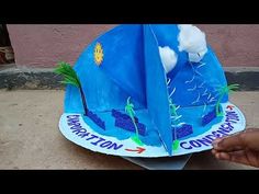 a paper boat that is sitting on the ground with clouds and water in it's sails