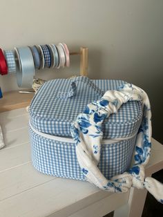 a blue and white checkered suitcase sitting on top of a wooden table next to ribbons