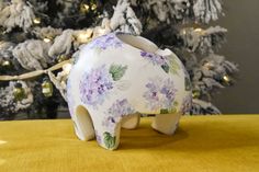 a ceramic elephant figurine sitting on top of a table next to a christmas tree