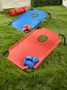 two red and blue bags sitting on top of a grass covered field next to each other