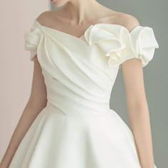 a woman in a white wedding dress with ruffles on the shoulders and shoulder