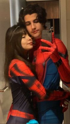 a man and woman dressed as spider - man are taking a selfie in the bathroom