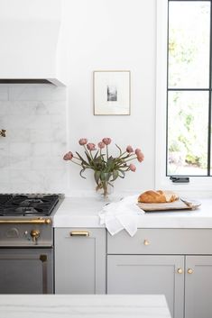 a white kitchen with marble counter tops and stainless steel appliances, including a stove top oven