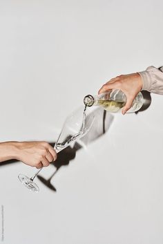 two people are holding wine glasses and pouring them into each other's beaks