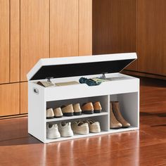 an open shoe box on the floor with several pairs of shoes in it next to wooden cabinets