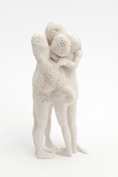 two figurines hugging each other on a white background