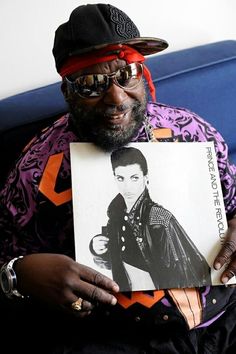 a man sitting on a couch holding up a poster