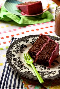 a slice of chocolate cake on a plate with a fork and spoon next to it