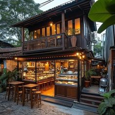 the outside of a restaurant with tables and stools in front of it at dusk