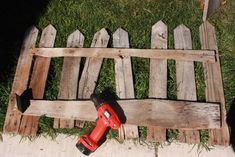 a cordless drill is laying on the ground next to a wooden pallet and fence