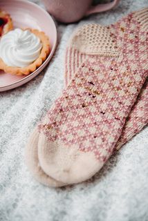 a pair of pink socks sitting on top of a bed next to a plate of food