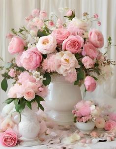 a white vase filled with pink flowers on top of a table next to other flowers