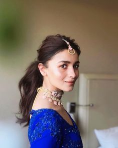 a woman wearing a blue dress and gold jewelry