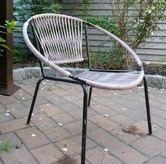 a white chair sitting on top of a brick patio next to a house and bushes