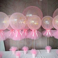 pink and gold balloons are hanging from the ceiling in front of a white tablecloth