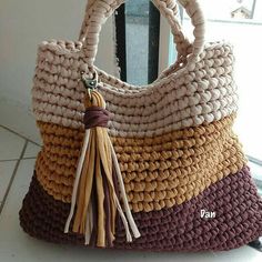 a handbag with tassels is sitting on the floor next to a window