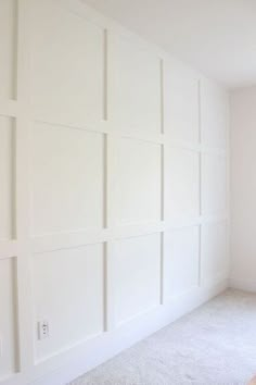 an empty room with white walls and carpet