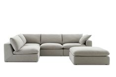 a large sectional couch sitting on top of a white floor next to a footstool