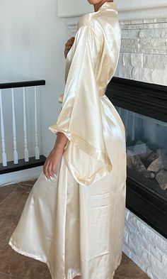 This soft gold silky floor-length robe is the perfect staple piece to own. A smooth belt drapes around to tie at the front, wrapping the fabric up softly. With a crisp neckline and wide sleeves, this kimono robe can be worn to lounge around comfortably, as a bridal robe, or to add a luxurious touch to relax in Night Robe Aesthetic, Silk Robe Aesthetic, Fancy Robes, Luxury Robes, Bridal Robe, Wedding Robe, Cream Silk, Silk Robe, Silk Gown